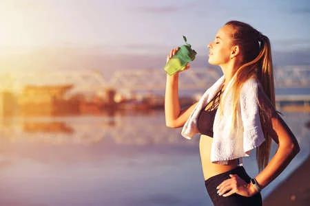 165330123-fitness-mujer-bebiendo-agua-después-de-correr-entrenamiento-en-el-río-de-la-mañana-y-el-fondo-de-la-