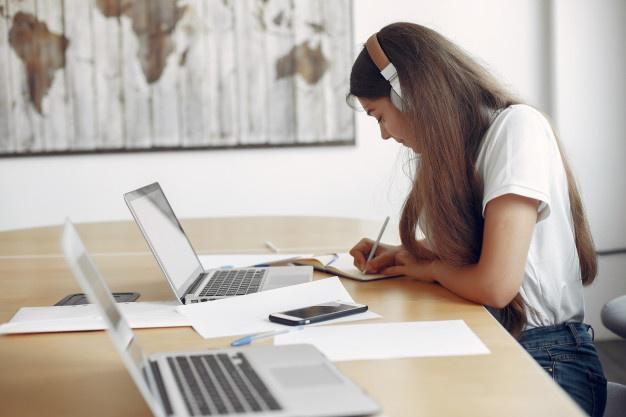 joven-estudiante-sentado-mesa-usar-computadora-portatil_1157-27557